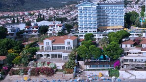 A coastal hotel with multiple balconies, a pool area, and a beach with sun loungers. - Arora Hotel (Kuşadası)