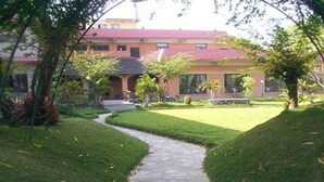 Un sendero conduce a un edificio de techo rojo, rodeado de césped cuidado y árboles.