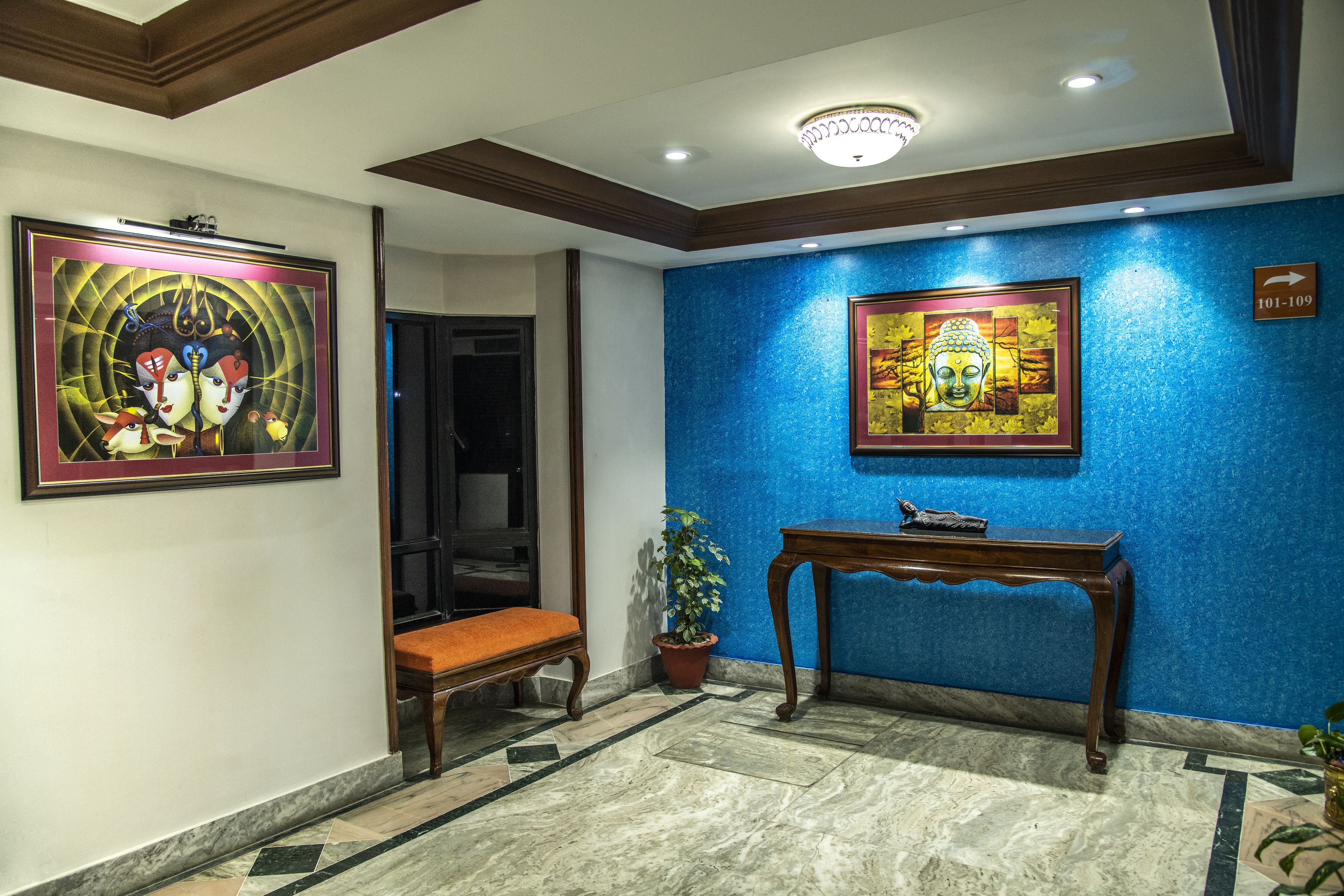 Un vestíbulo con pared azul, un banco de madera, una consola y dos obras de arte enmarcadas.