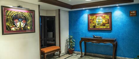 Un vestíbulo con pared azul, un banco de madera, una consola y dos obras de arte enmarcadas.