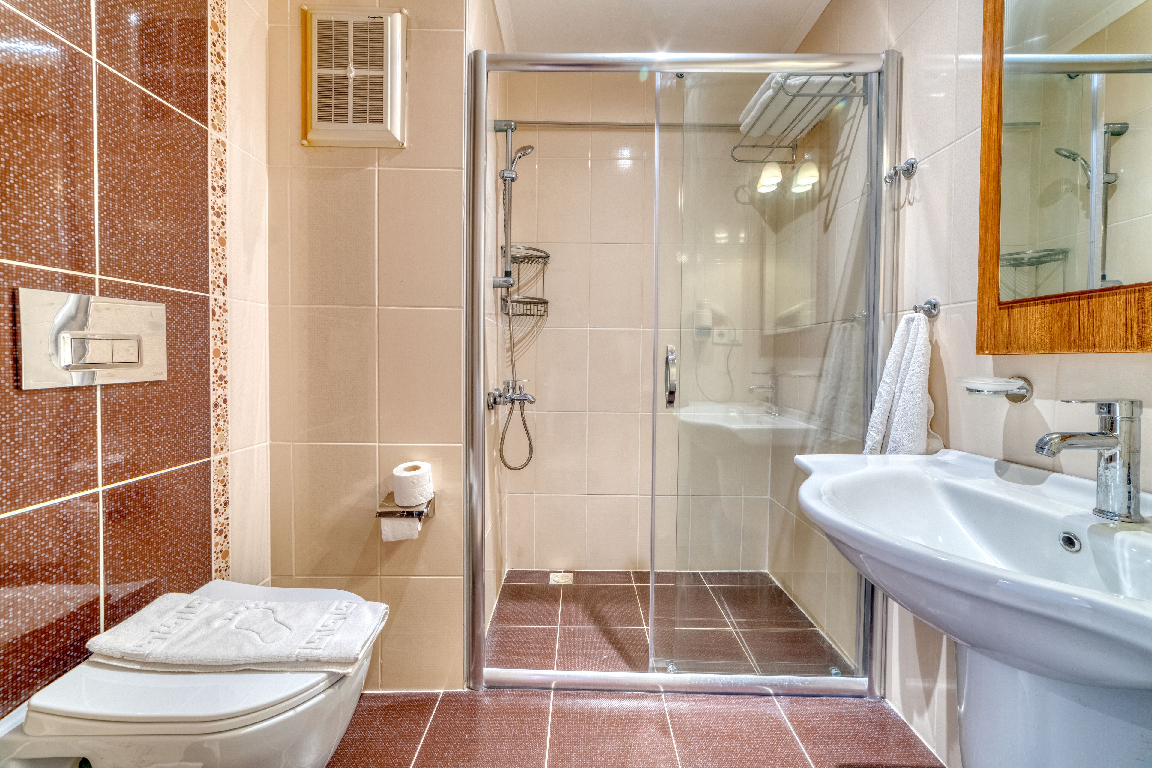 Un baño moderno con ducha acristalada, lavabo blanco y retrete.