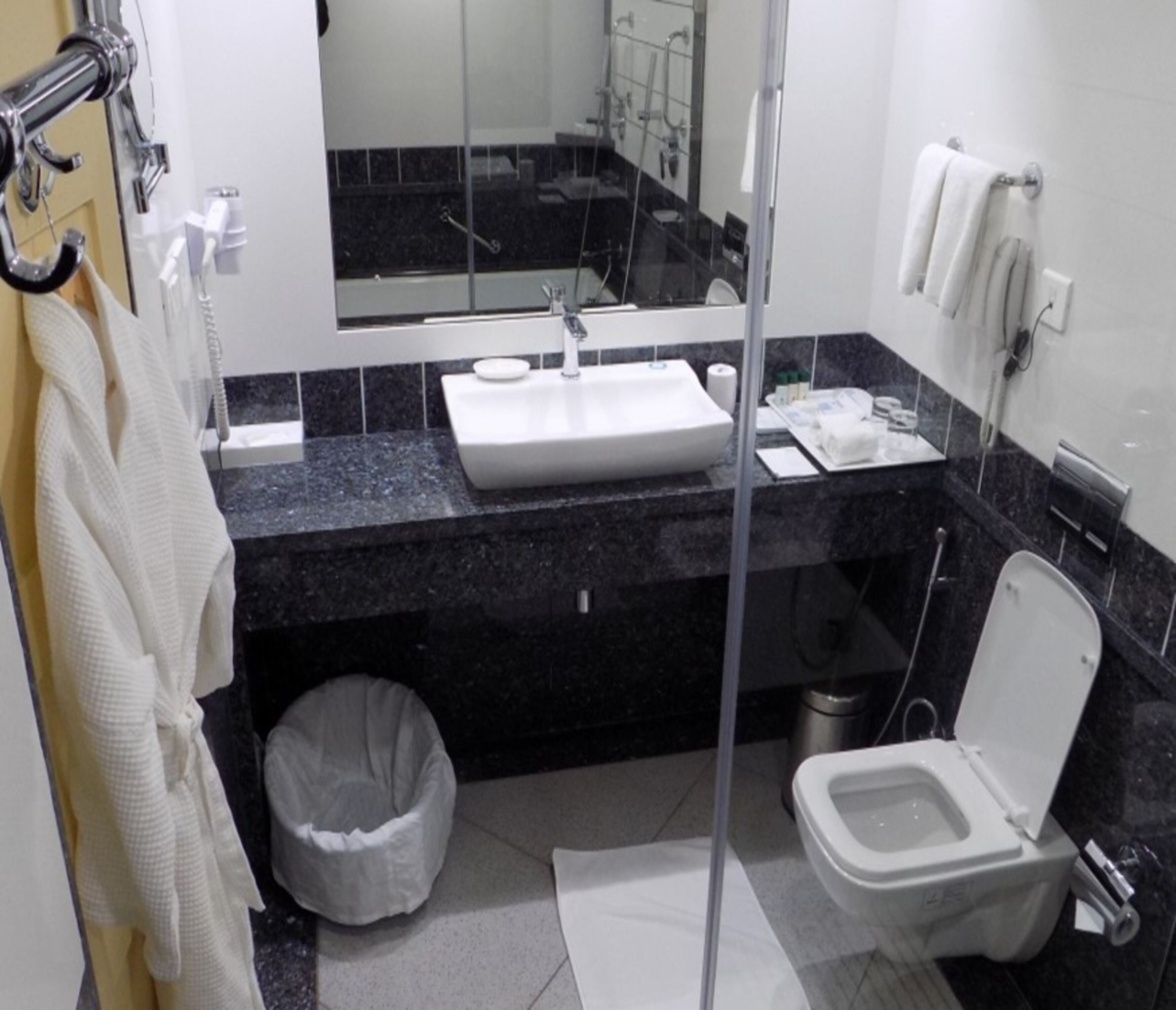 Un bagno con lavandino, specchio, WC e cestino.