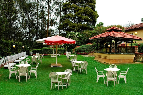Un patio al aire libre con varias mesas y sillas, un pabellón y una valla blanca.