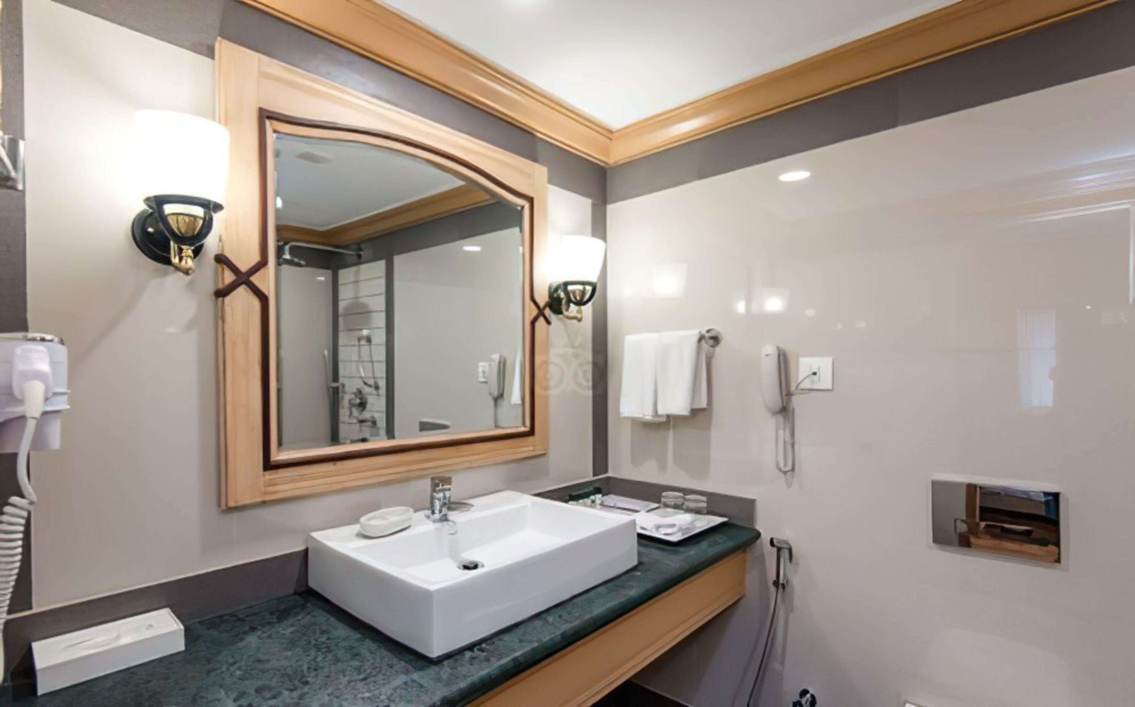 Un baño moderno con un espejo grande, un lavamanos blanco y una zona de ducha.