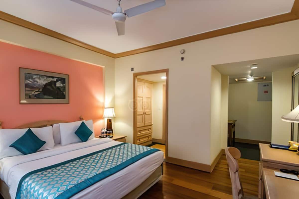 Ein Hotelzimmer mit Bett, Nachttisch, Lampe und einem Gemälde an der Wand.