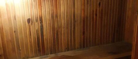 A wooden interior with vertical planks and a wooden bench.