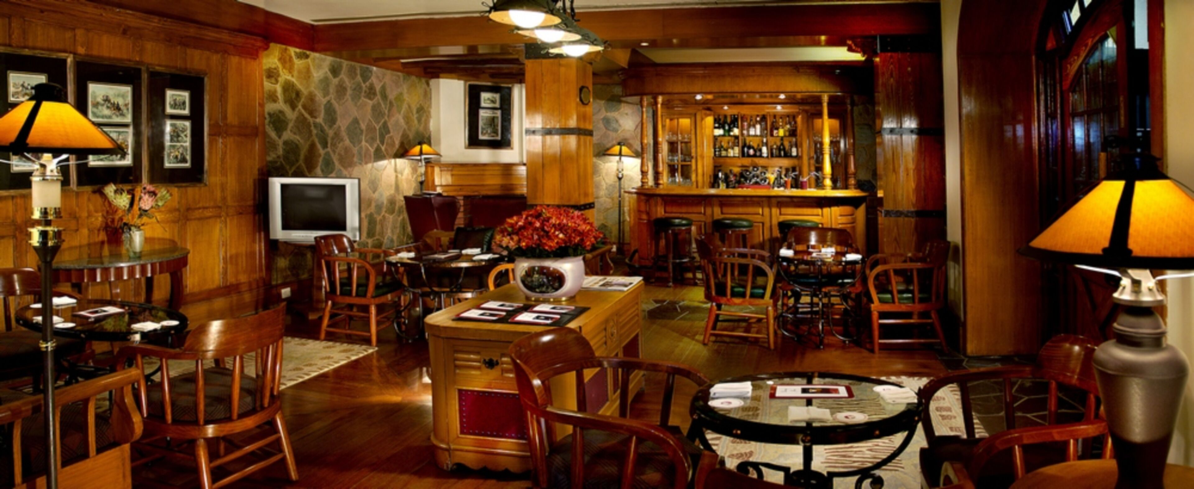 A bar area with wooden furniture, a television, and a bar stocked with bottles.