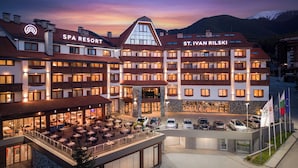 Un hôtel à plusieurs étages, avec un panneau indiquant la présence d’une station de ski, un restaurant doté d’une terrasse et des drapeaux.