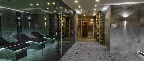 A modern bathroom with glass-enclosed sinks, a stone wall, and a marble floor.