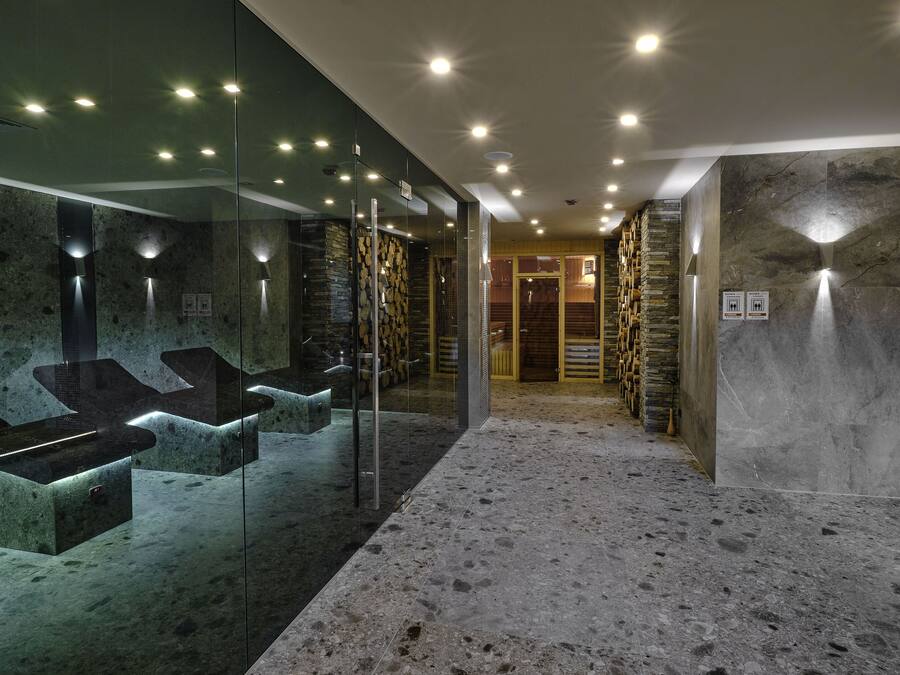 A modern bathroom with glass-enclosed sinks, a stone wall, and a marble floor.