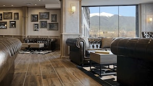 Un salon spacieux avec des canapés en cuir, une table basse en bois et des tableaux encadrés aux murs.