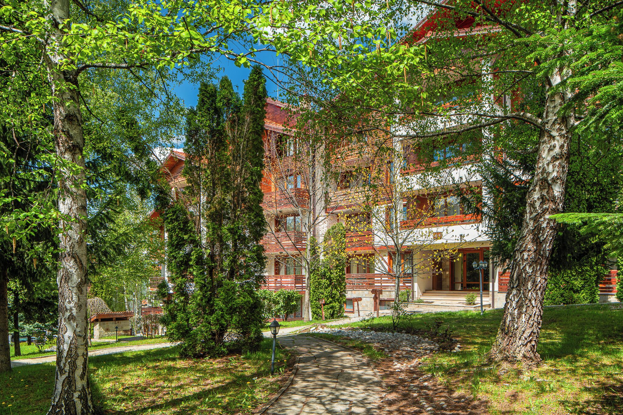 A building with multiple floors, surrounded by trees and a pathway.