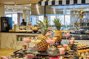 Un bufé con diversas opciones de comida y bebidas, incluyendo frutas tropicales y postres.