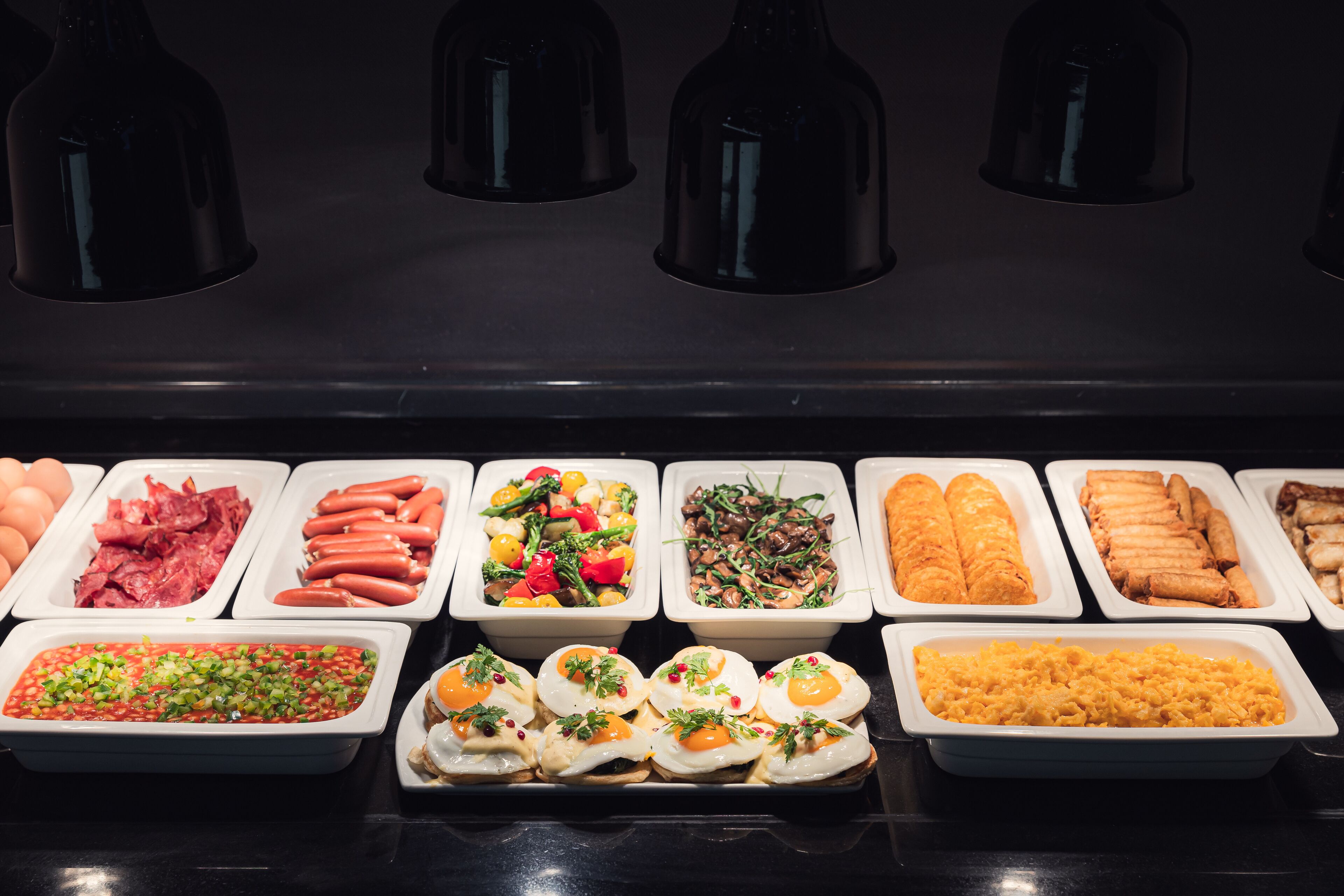 A buffet with various food items including eggs, sausages, salads, and other dishes.
