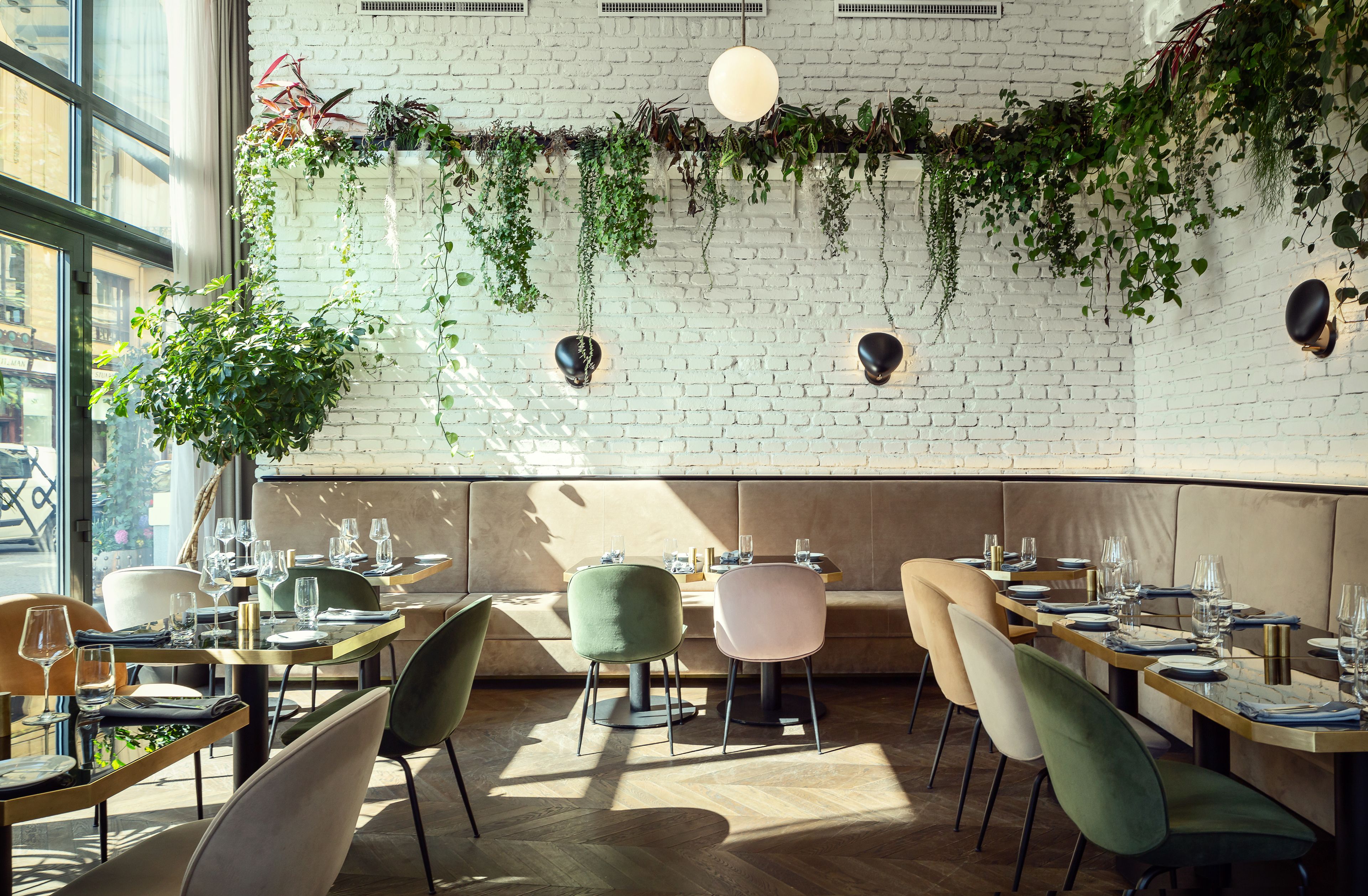 A restaurant with brick walls, hanging plants, and modern furniture.