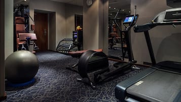 Un gimnasio con cinta de correr, pelota de ejercicios y diverso equipamiento de fitness.