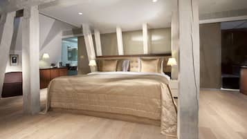 Um quarto espaçoso com uma cama grande, vigas de madeira, uma escrivaninha de madeira e um espelho.