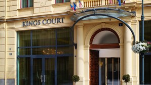Fachada del hotel Kings Court con una entrada destacada, ventanas amplias y un balcón con banderas.