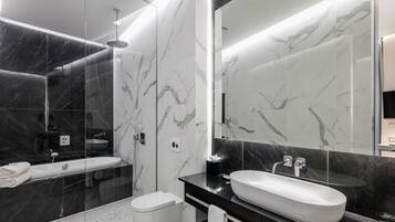 Une salle de bain moderne avec un grand miroir, une baignoire et des toilettes.