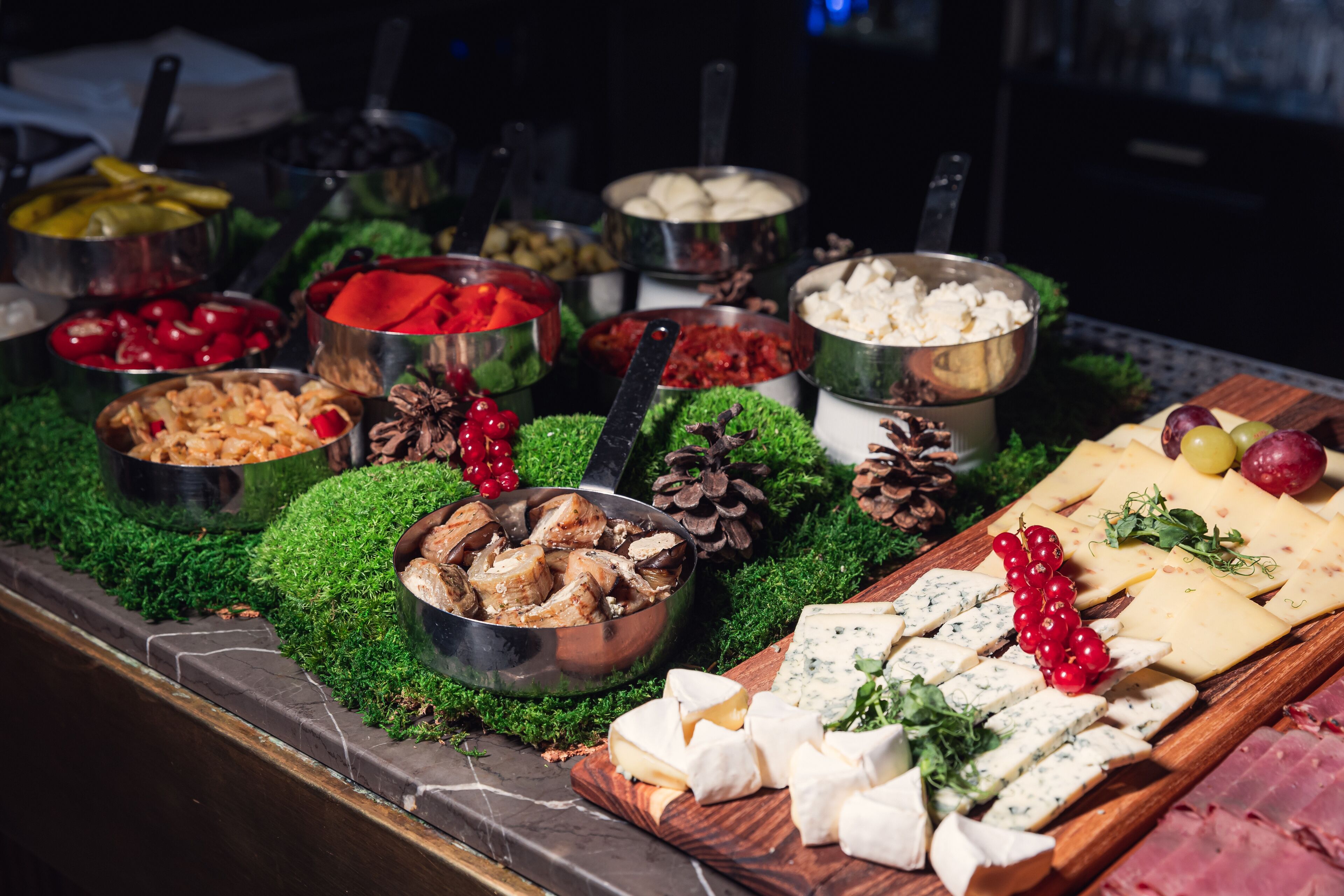 A buffet with various cheeses, meats, and fruits.
