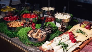 A buffet with various cheeses, meats, and fruits.
