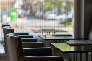 Eine Reihe von schwarzen Stühlen und Tischen in einem Café mit Blick auf die Straße.