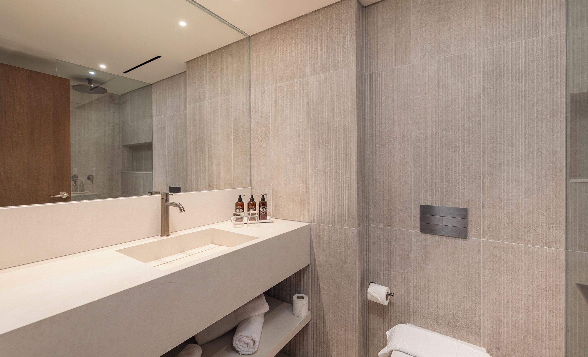 Un baño moderno con un espejo grande, un lavamanos y un perchero para toallas.