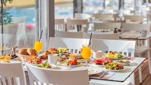 A dining area with tables set for breakfast, featuring a variety of dishes and orange juice. - Brown Dead Sea by Brown Hotels (Tamar)
