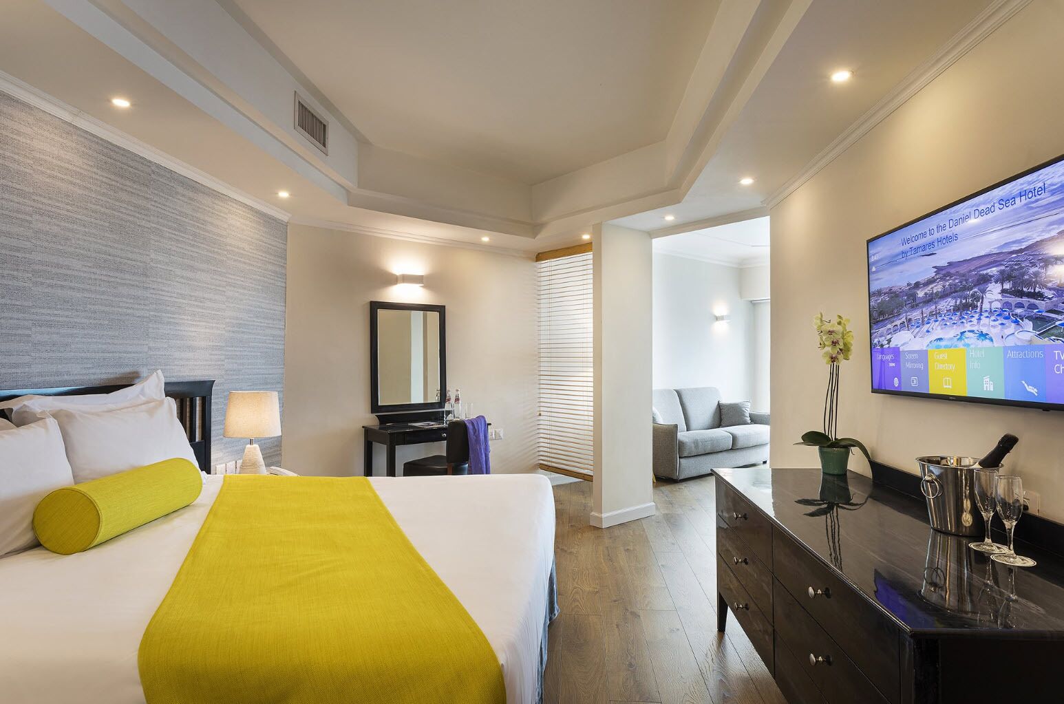 A hotel room with a bed, a desk, a television, and a view of the outside.