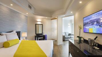 A hotel room with a bed, a desk, a television, and a view of the outside.
