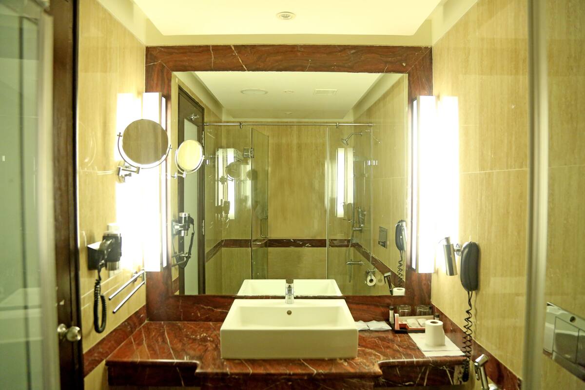 A bathroom with a double sink, a mirror, a hairdryer, and a telephone.