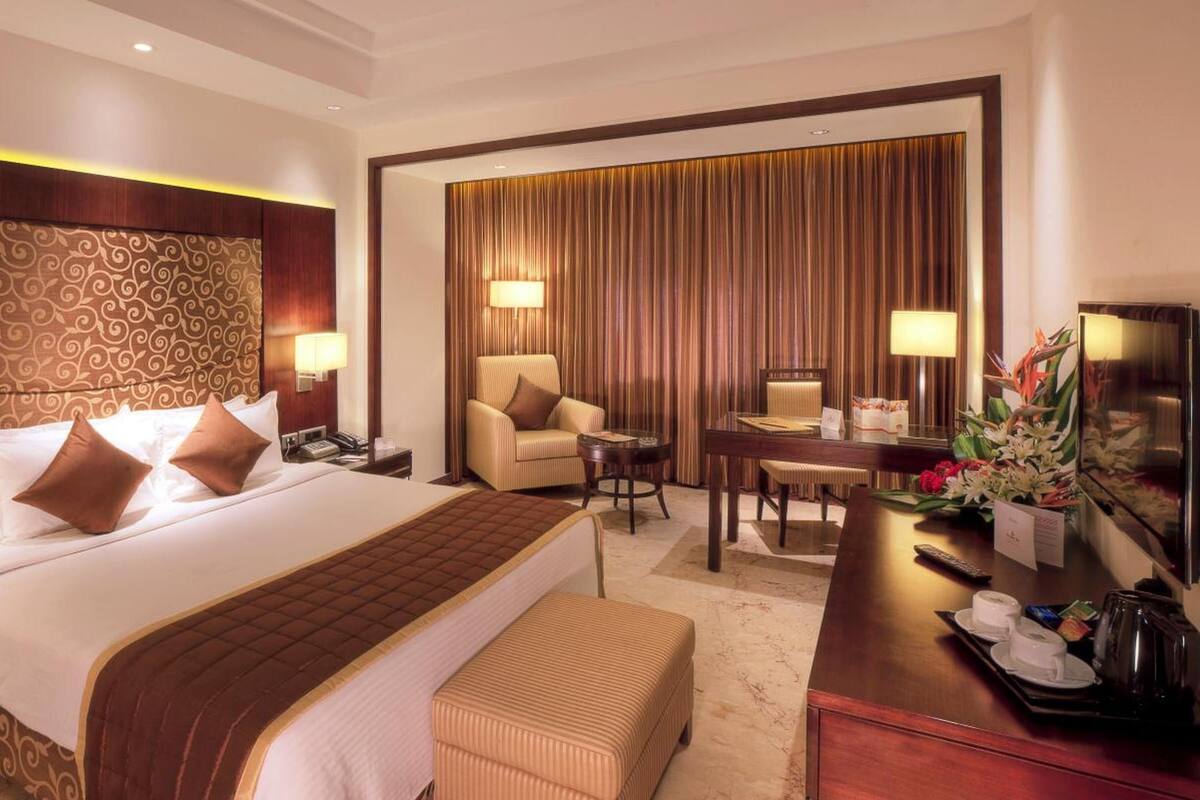 A hotel room with a large bed, a desk, a chair, and a television.