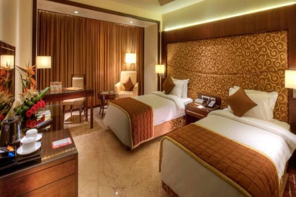 A hotel room with two beds, a desk with a telephone, and a seating area with a table and chairs.