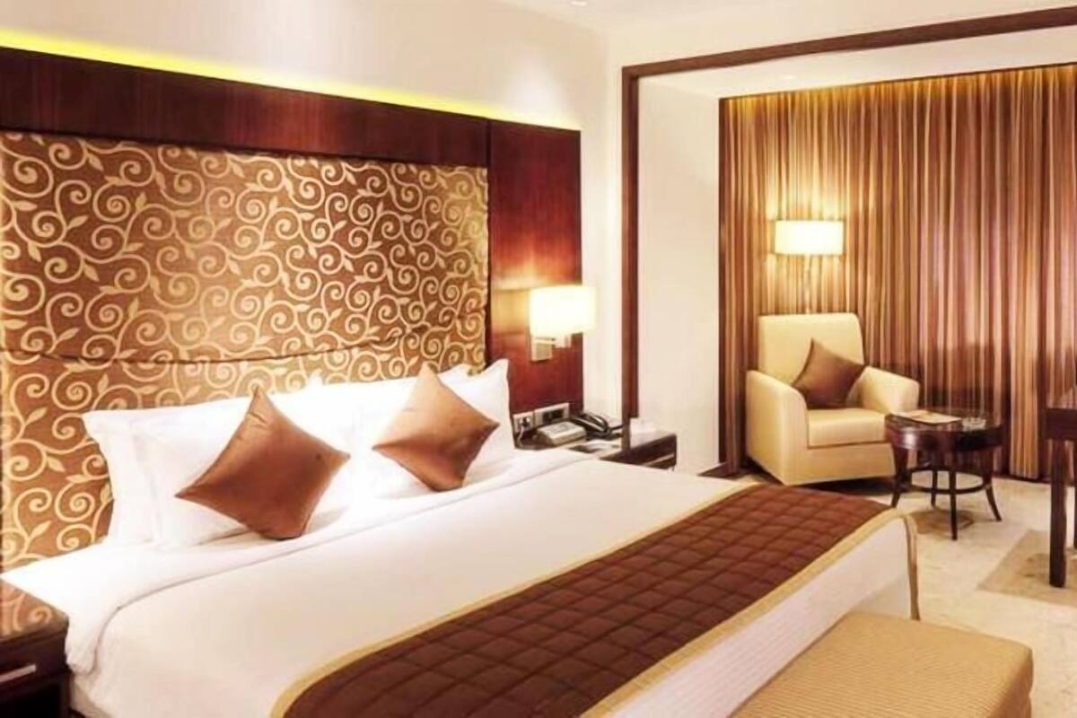 A hotel room with a large bed, a desk, a chair, and a sofa.