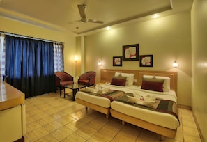 A hotel room with a bed, two chairs, a small table, and a desk. - Vishwaratna Hotel (Guwahati)