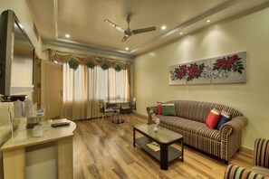 A living room with a sofa, coffee table, and a dining area with chairs and a table. - Vishwaratna Hotel (Guwahati)
