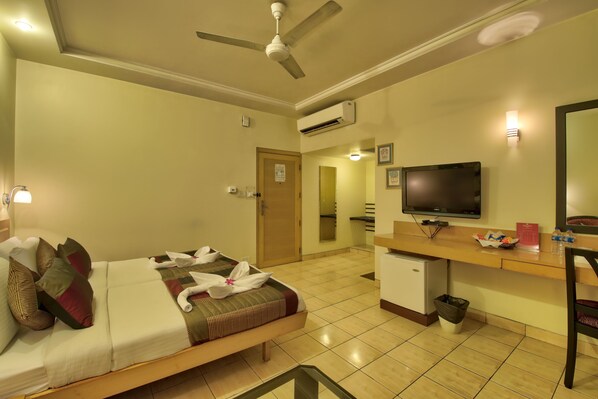 A hotel room with a bed, a desk, a television, and a ceiling fan.