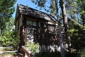 A lodge with a stone foundation, wooden deck, and a staircase leading to the entrance.