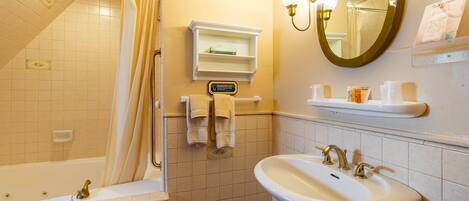 Un baño con bañera, lavabo, espejo y toallero.