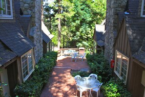 A brick pathway leading to a patio area with a table and chairs, surrounded by stone walls and greenery.