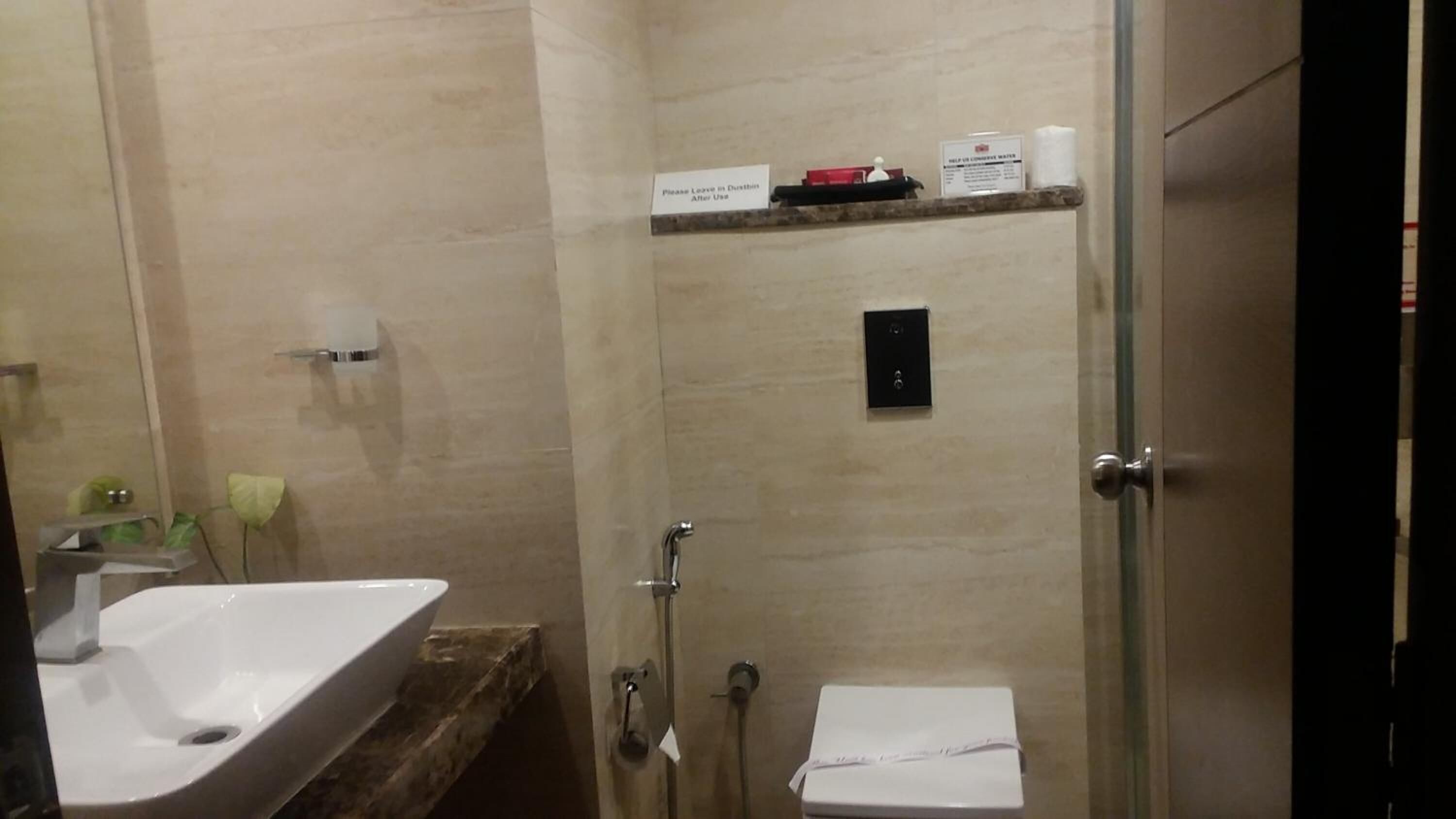 A bathroom with a sink, toilet, and shower. There are toiletries on a shelf.