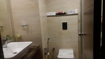 A bathroom with a sink, toilet, and shower. There are toiletries on a shelf.