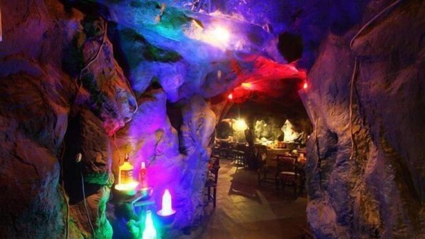 Un intérieur qui rappelle une grotte, avec un éclairage coloré et un bar visible au fond.