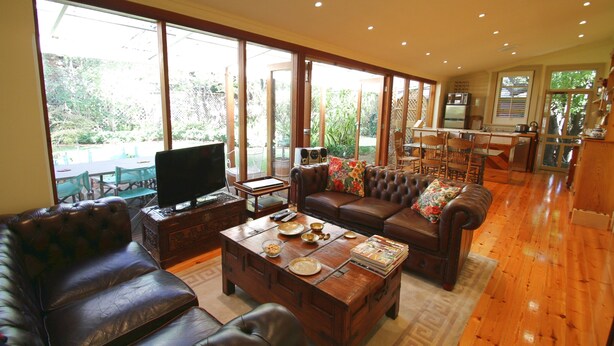 Ein geräumiger Wohnbereich mit einem großen Couchtisch aus Holz, Ledersofas und einem Fernseher.