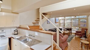 Eine moderne Küche mit Einbauherd, Spüle und einer Treppe, die in einen Essbereich mit Tisch und Stühlen führt.
