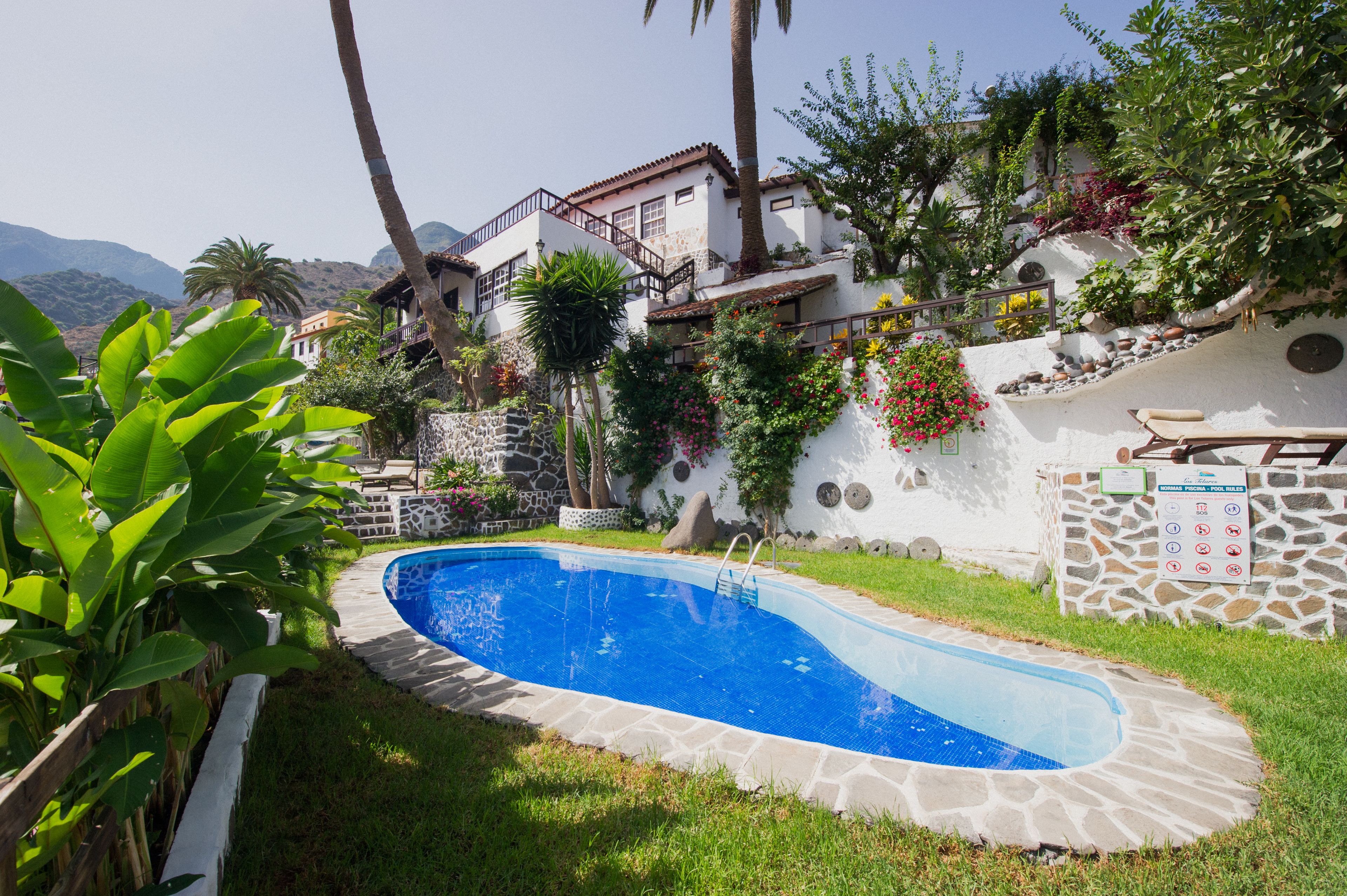 A swimming pool surrounded by a stone wall, with a stone staircase leading up to a building.