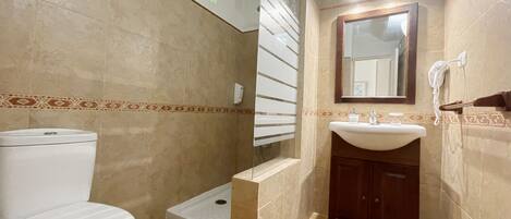 Un baño con inodoro, ducha y lavamanos.