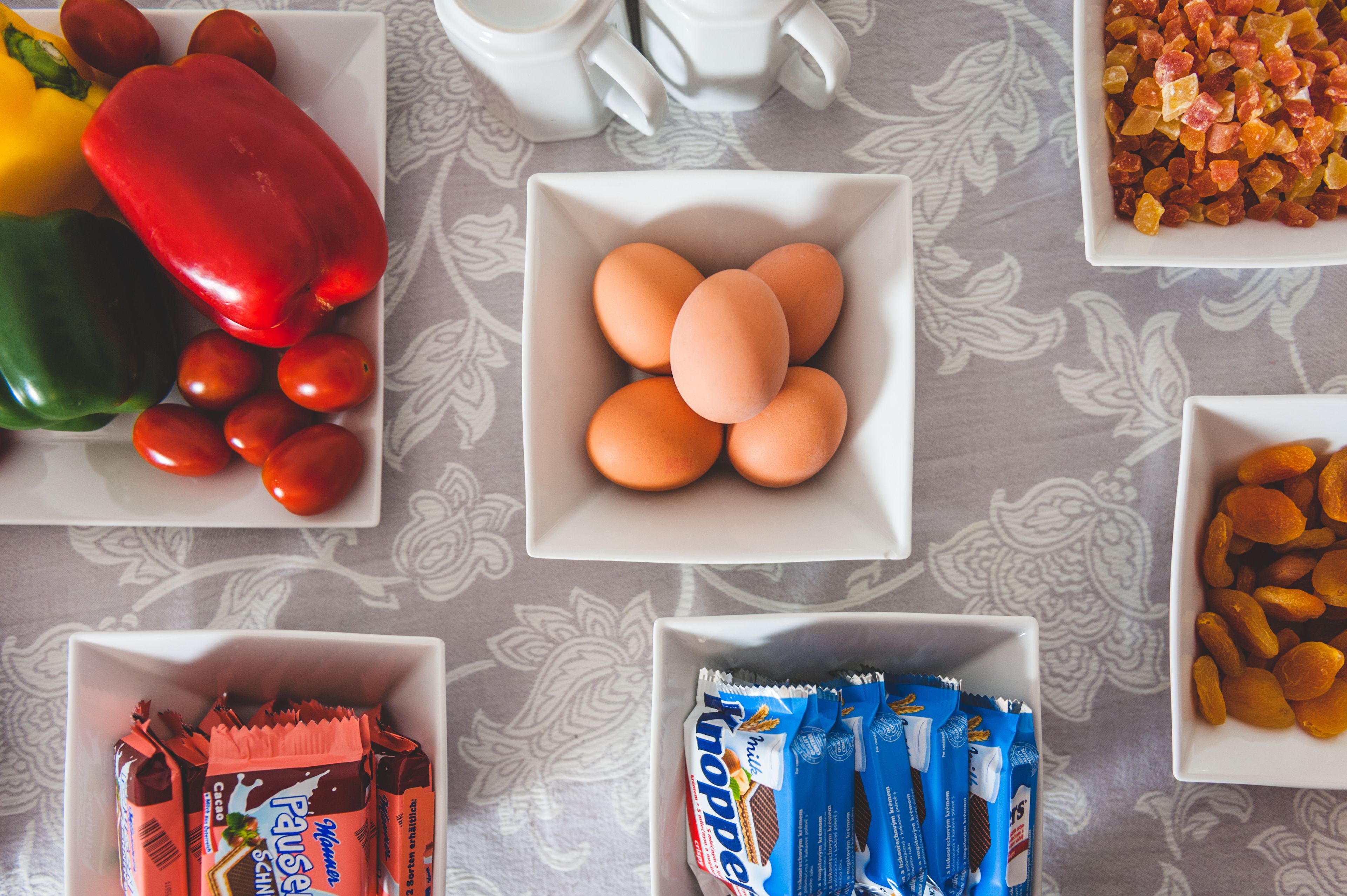 A table with various food items including eggs, tomatoes, bell peppers, and dried fruits.