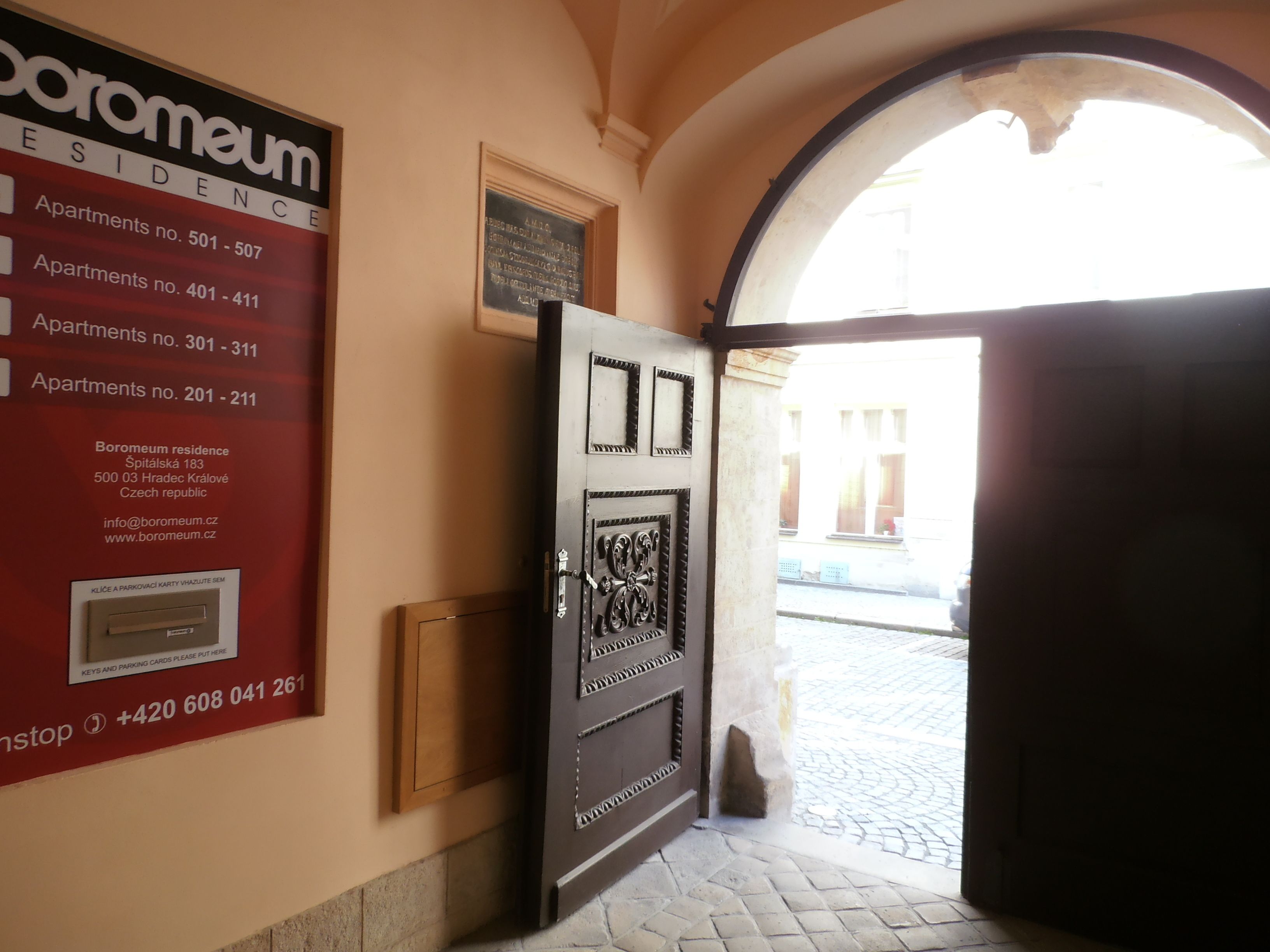 Ein Hotel Eingang mit einem Schild, das Apartmentnummern und Kontaktinformationen auflistet.