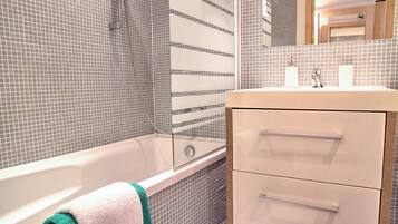 A bathroom with a bathtub, a sink, and a mirror.